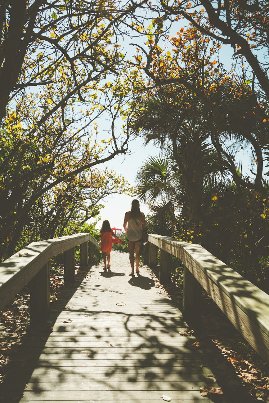 mother and daughter walking on sunlit pathway