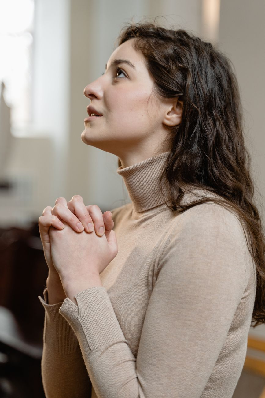 a woman in brown turtleneck sweater praying